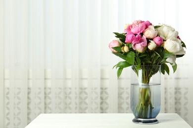 Bouquet of beautiful peonies in vase on white table. Space for text