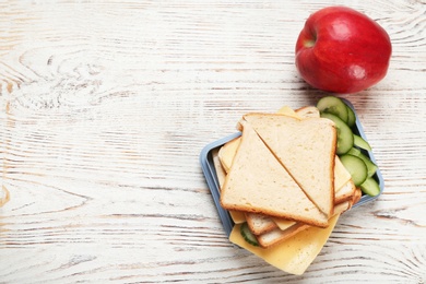 Lunch box with tasty sandwich on wooden table