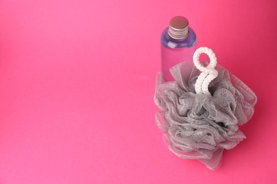 Grey shower puff and bottle of cosmetic product on pink background, space for text