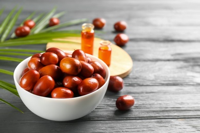 Photo of Palm oil fruits in bowl on grey wooden table, closeup