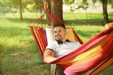 Photo of Young man resting in comfortable hammock at green garden