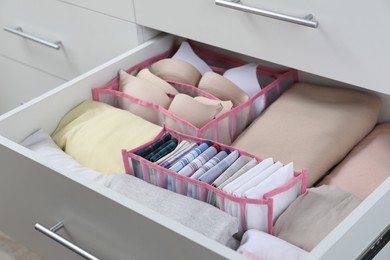 Photo of Open drawer with folded handkerchiefs and clothes, closeup