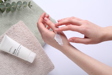 Woman applying hand cream on white background, above view