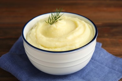 Photo of Freshly cooked homemade mashed potatoes with napkin on wooden table, closeup