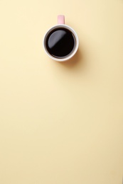 Ceramic cup with hot aromatic coffee on color background, top view