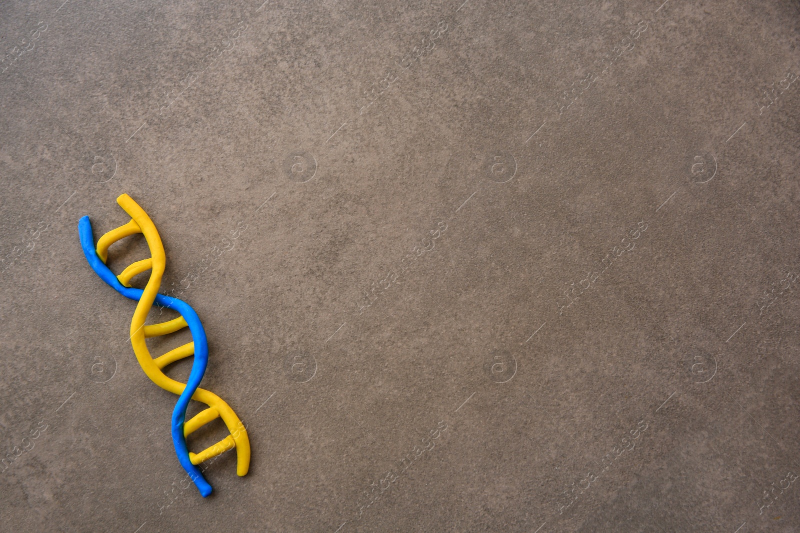 Photo of DNA molecule model made of colorful plasticine on brown background, top view. Space for text