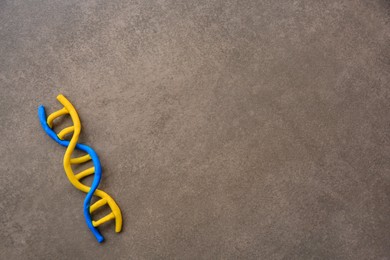 Photo of DNA molecule model made of colorful plasticine on brown background, top view. Space for text