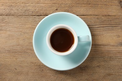 Photo of Tasty coffee in cup on wooden table, top view