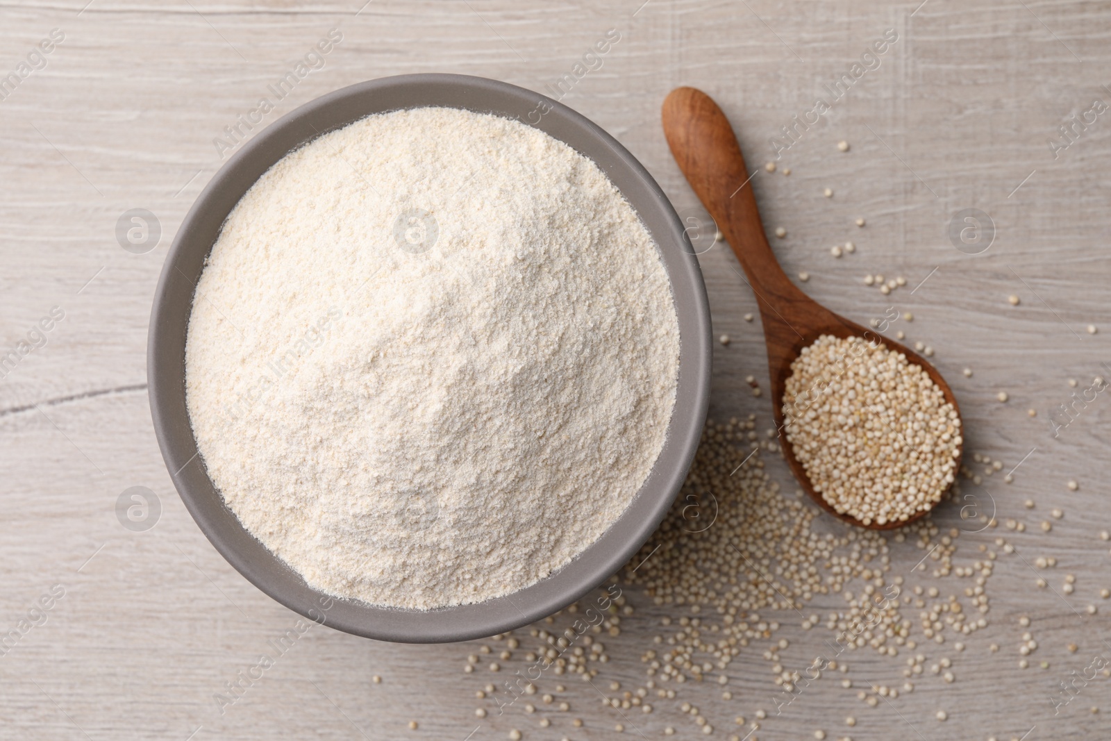 Photo of Ceramic bowl with quinoa flour and seeds on wooden table, flat lay