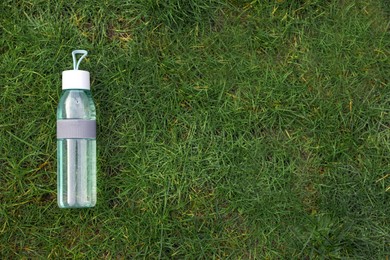 Bottle of water on green grass, top view with space for text. Morning exercise