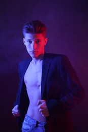 Photo of Sexy young man on dark background in neon lights