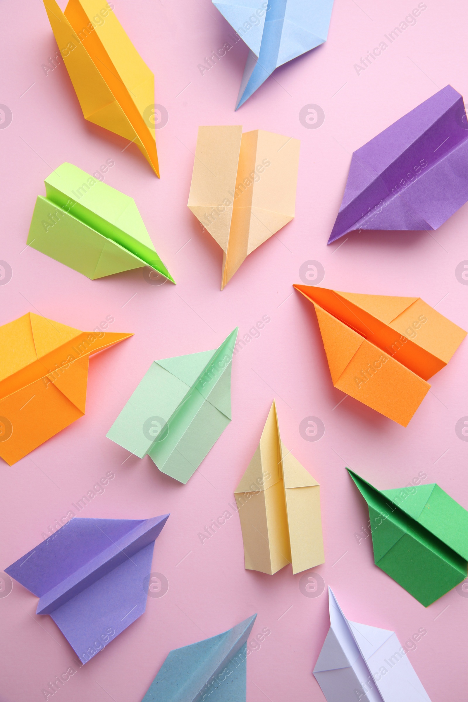 Photo of Many colorful paper planes on pink background, flat lay. Diversity concept