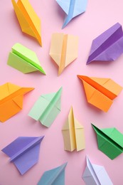 Photo of Many colorful paper planes on pink background, flat lay. Diversity concept