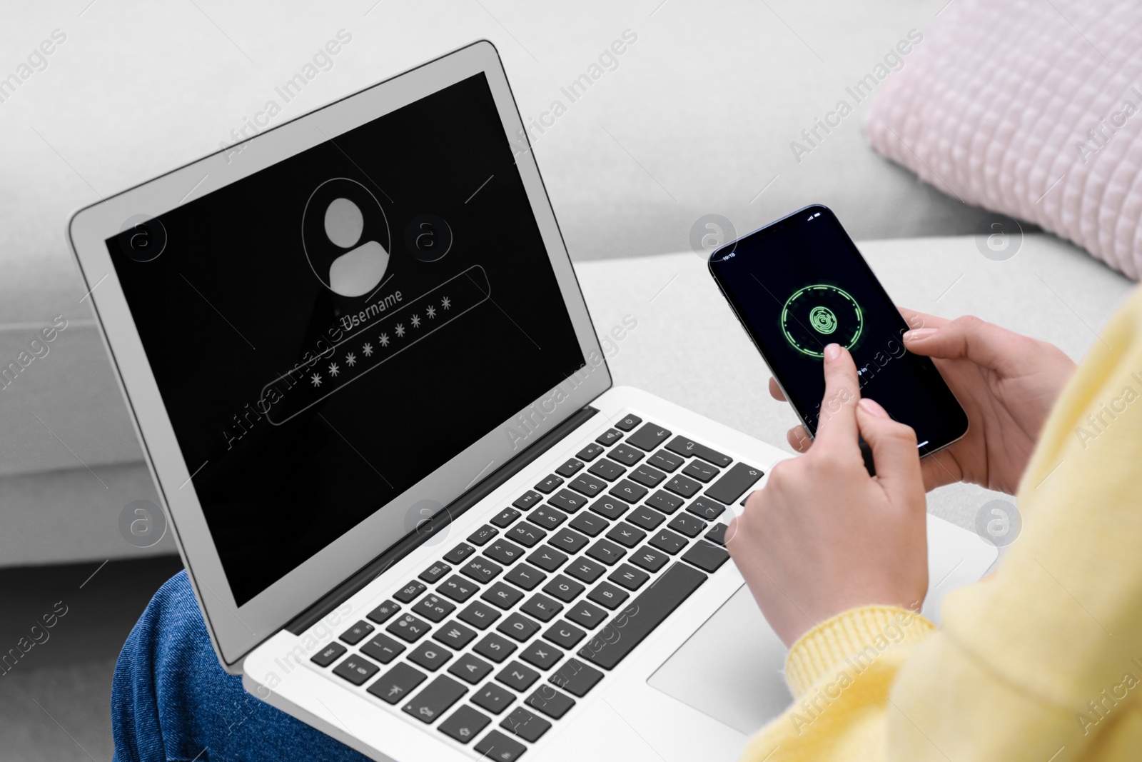 Photo of Woman unlocking smartphone with fingerprint scanner, closeup. Her laptop password protected to