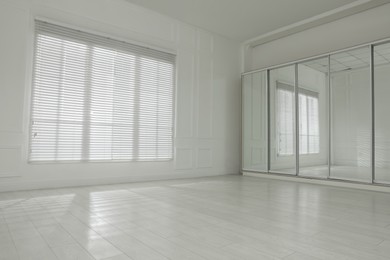 Photo of Empty room with white walls, large window and wooden floor