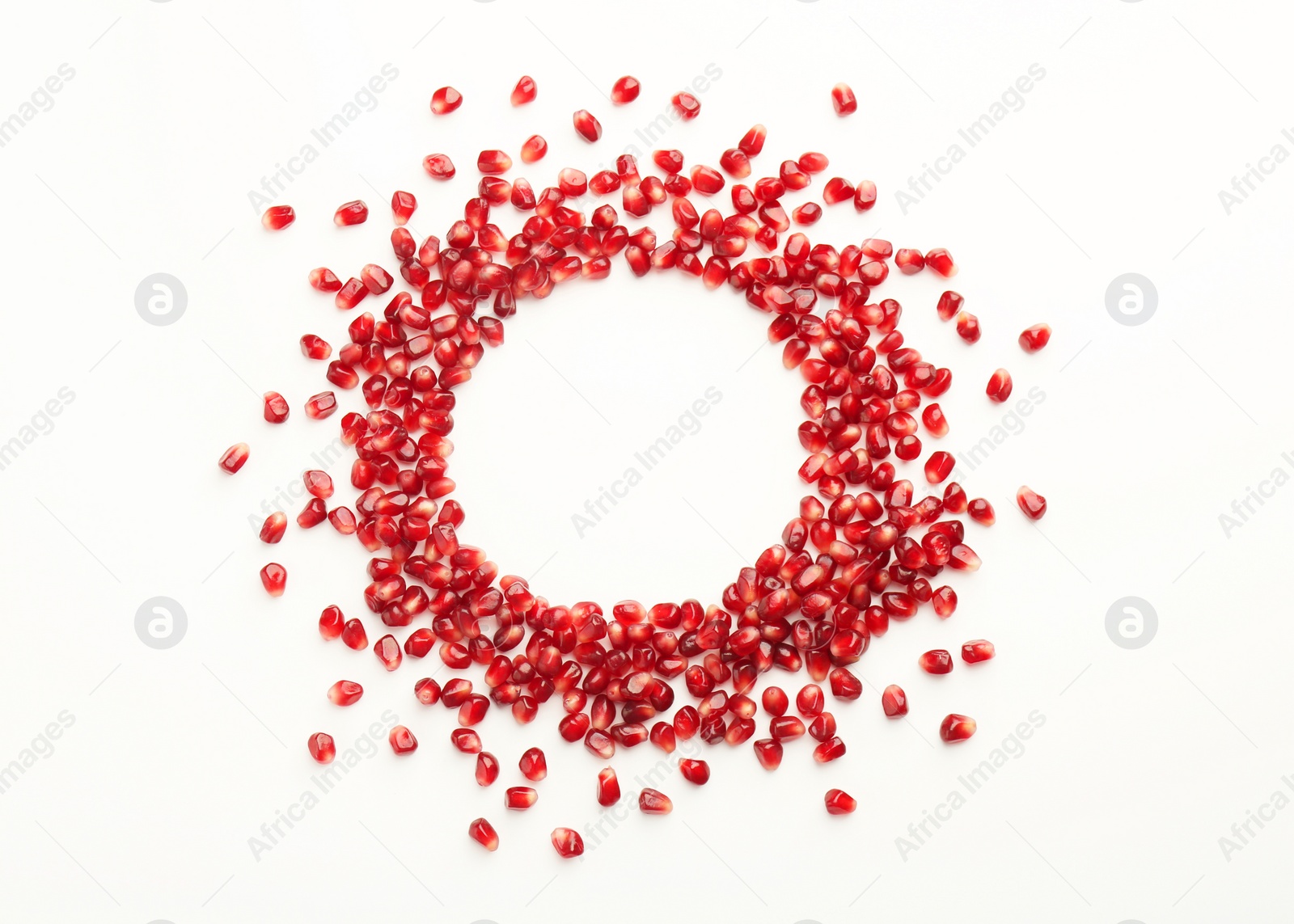 Photo of Frame made of ripe juicy pomegranate grains on white background, top view. Space for text