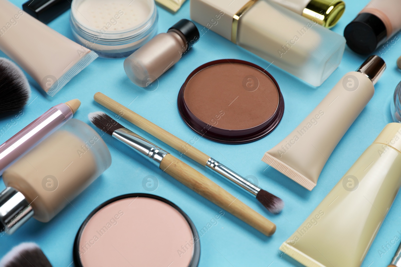 Photo of Face powders and other decorative cosmetic products on light blue background