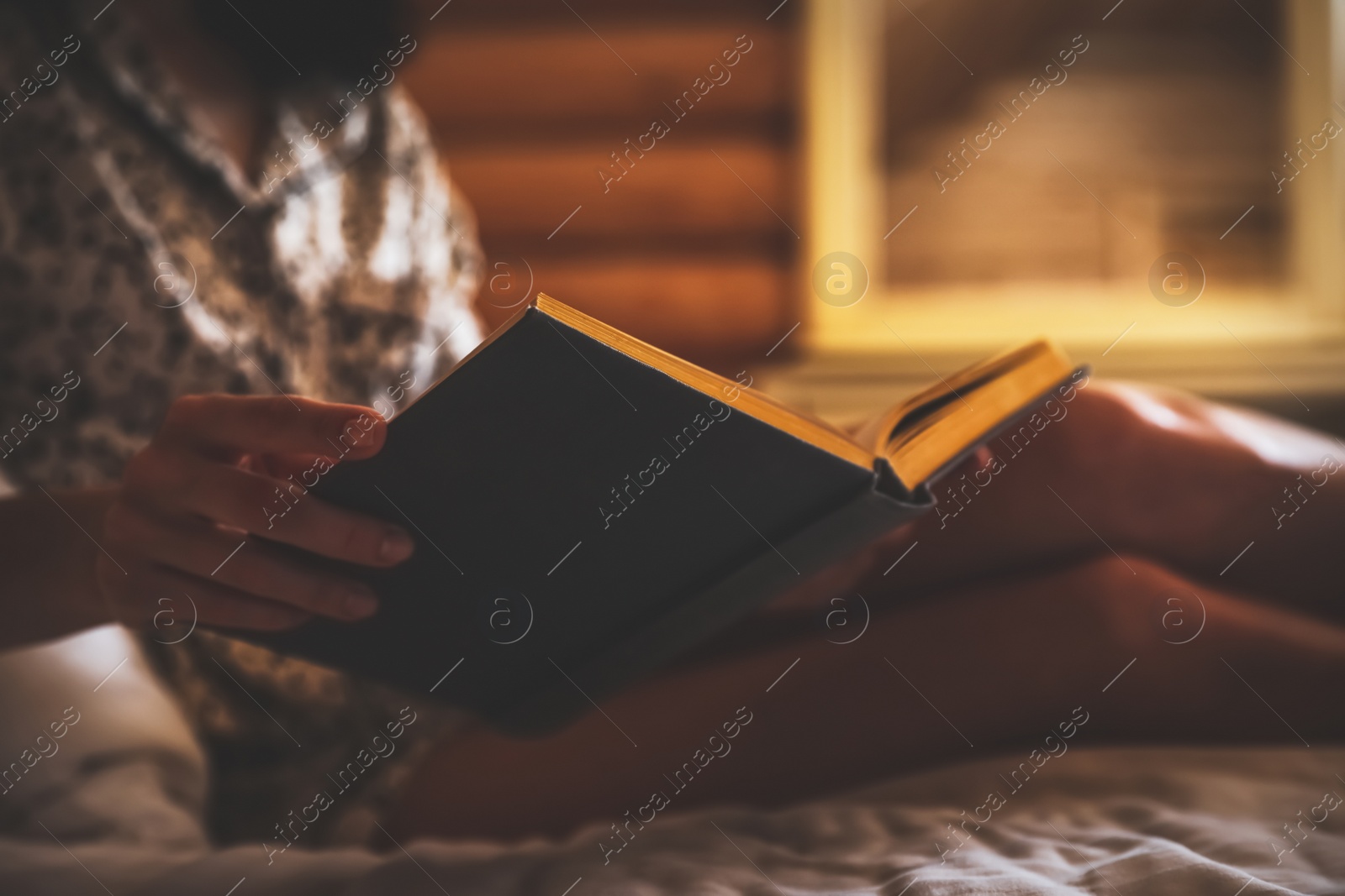 Photo of Woman reading book on bed at home, closeup