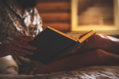 Photo of Woman reading book on bed at home, closeup