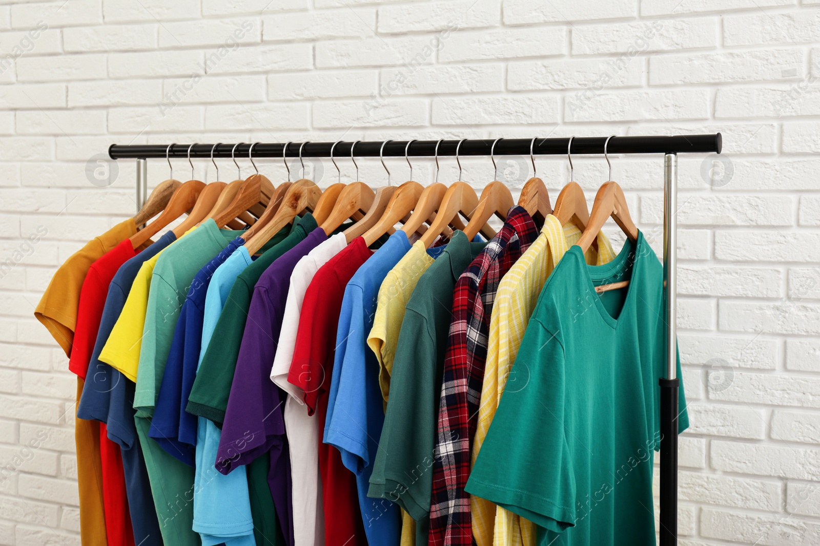 Photo of Rack with stylish clothes near white brick wall