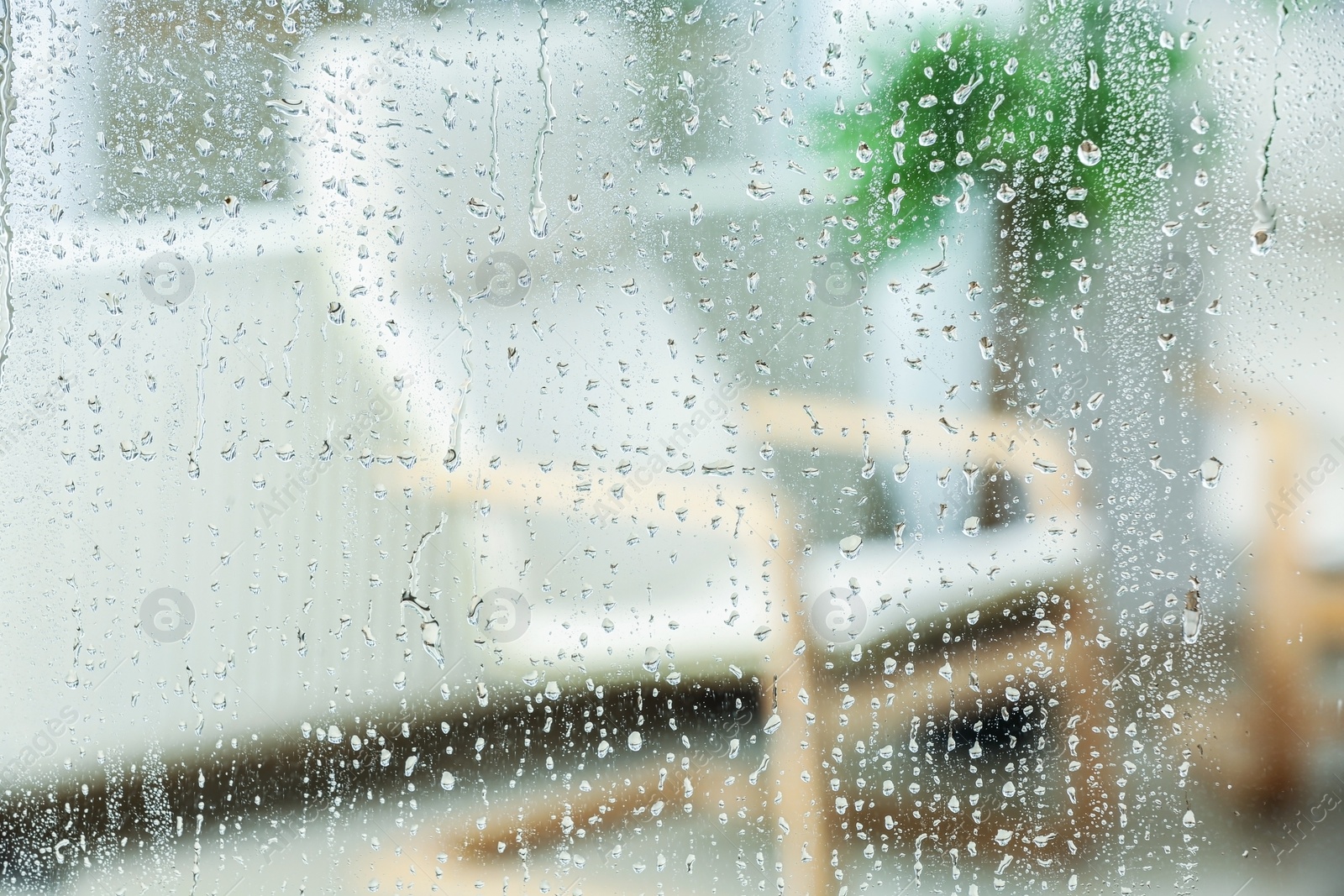 Photo of Blurred view of room through glass with water drops, closeup