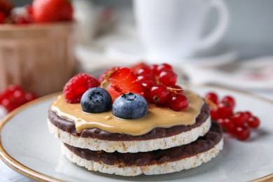 Photo of Crunchy rice cakes with peanut butter and sweet berries on plate, closeup