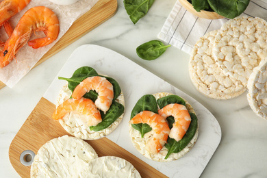Photo of Crunchy rice cakes with shrimps and basil on white marble table, flat lay