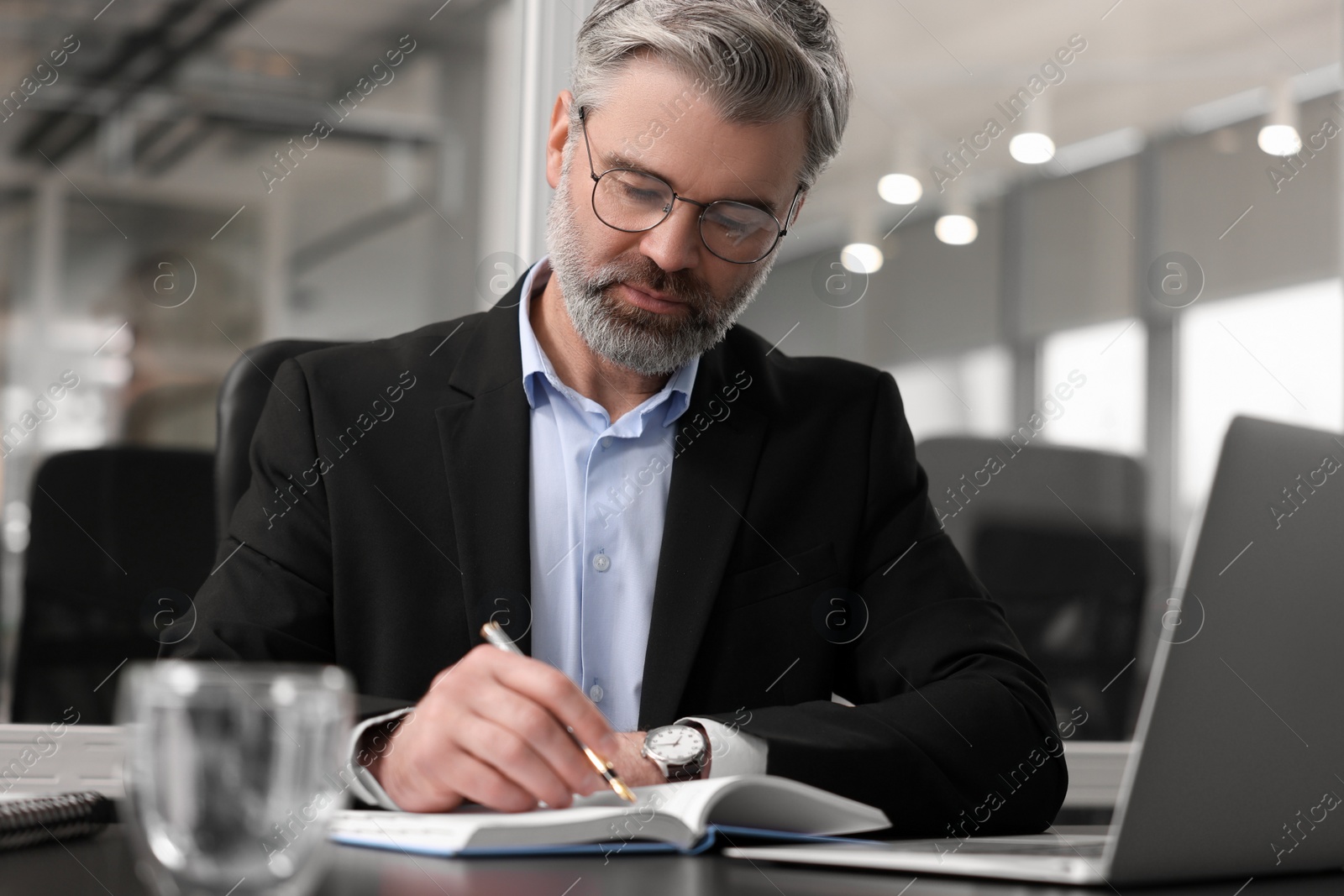 Photo of Handsome man working at table in office. Lawyer, businessman, accountant or manager