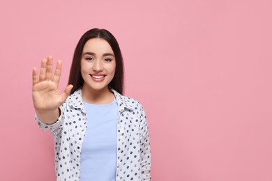 Photo of Happy woman giving high five on pink background, space for text