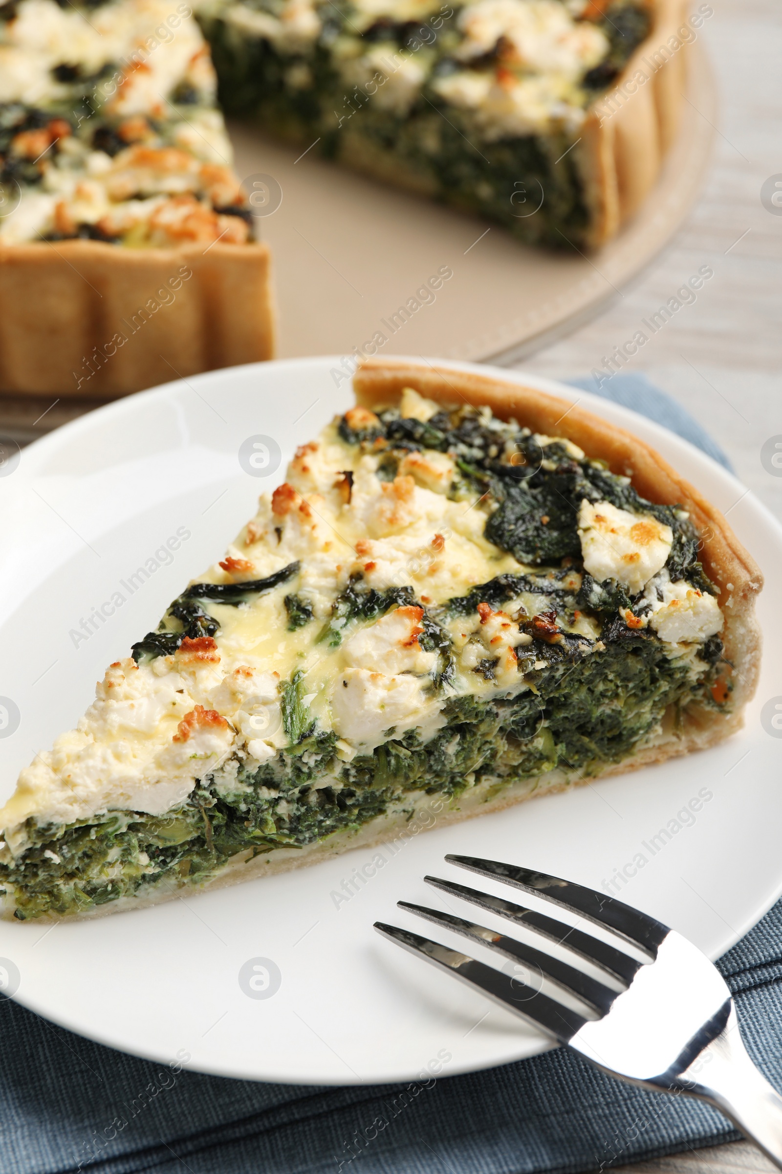 Photo of Piece of delicious homemade spinach quiche on plate, closeup