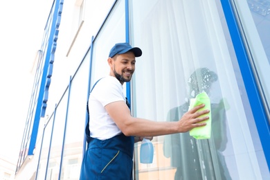 Photo of Male worker washing window glass from outside