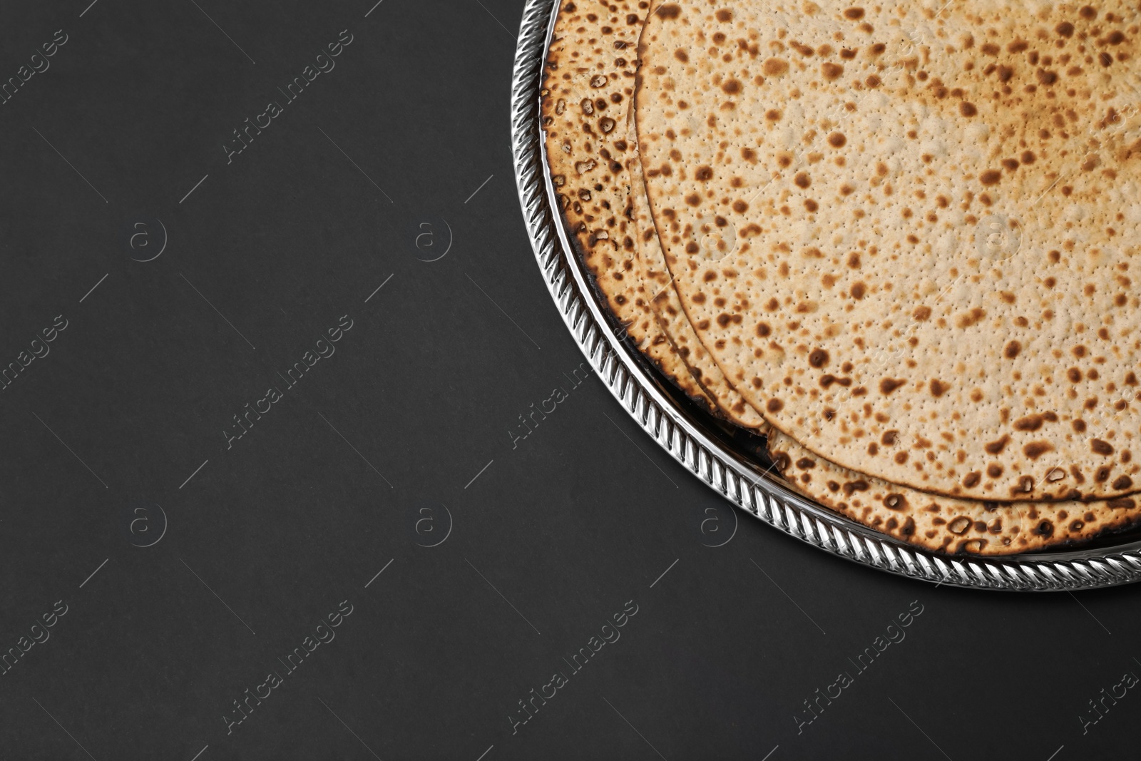 Photo of Tasty matzos on black background, top view with space for text. Passover (Pesach) celebration