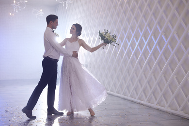 Photo of Happy newlywed couple dancing together in festive hall