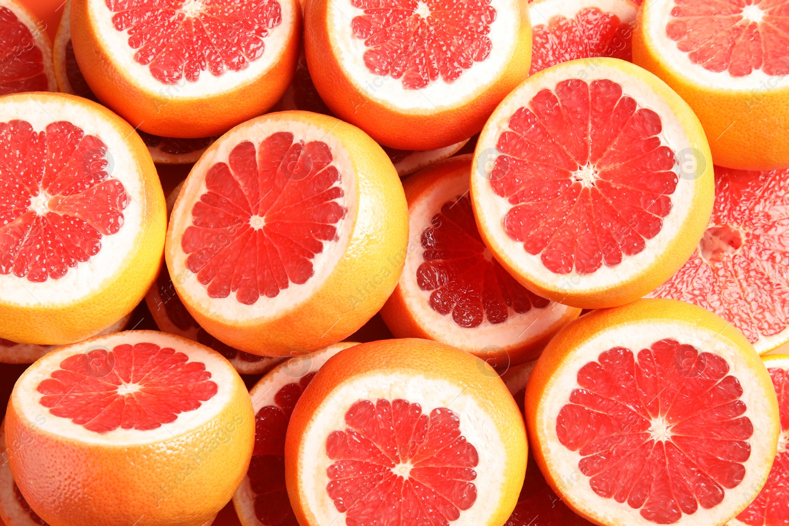 Photo of Many sliced fresh grapefruits as background, top view