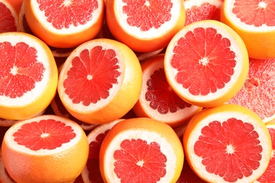 Many sliced fresh grapefruits as background, top view