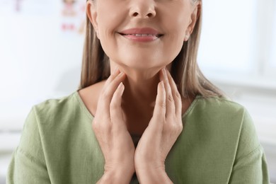Photo of Endocrine system. Senior woman doing thyroid self examination indoors, closeup