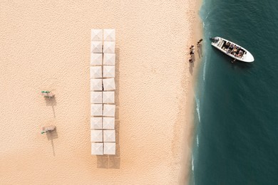 Image of Motorboat near sandy coast with beach umbrellas, aerial view. Summer vacation