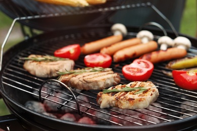 Barbecue grill with meat, sausages and vegetables outdoors, closeup