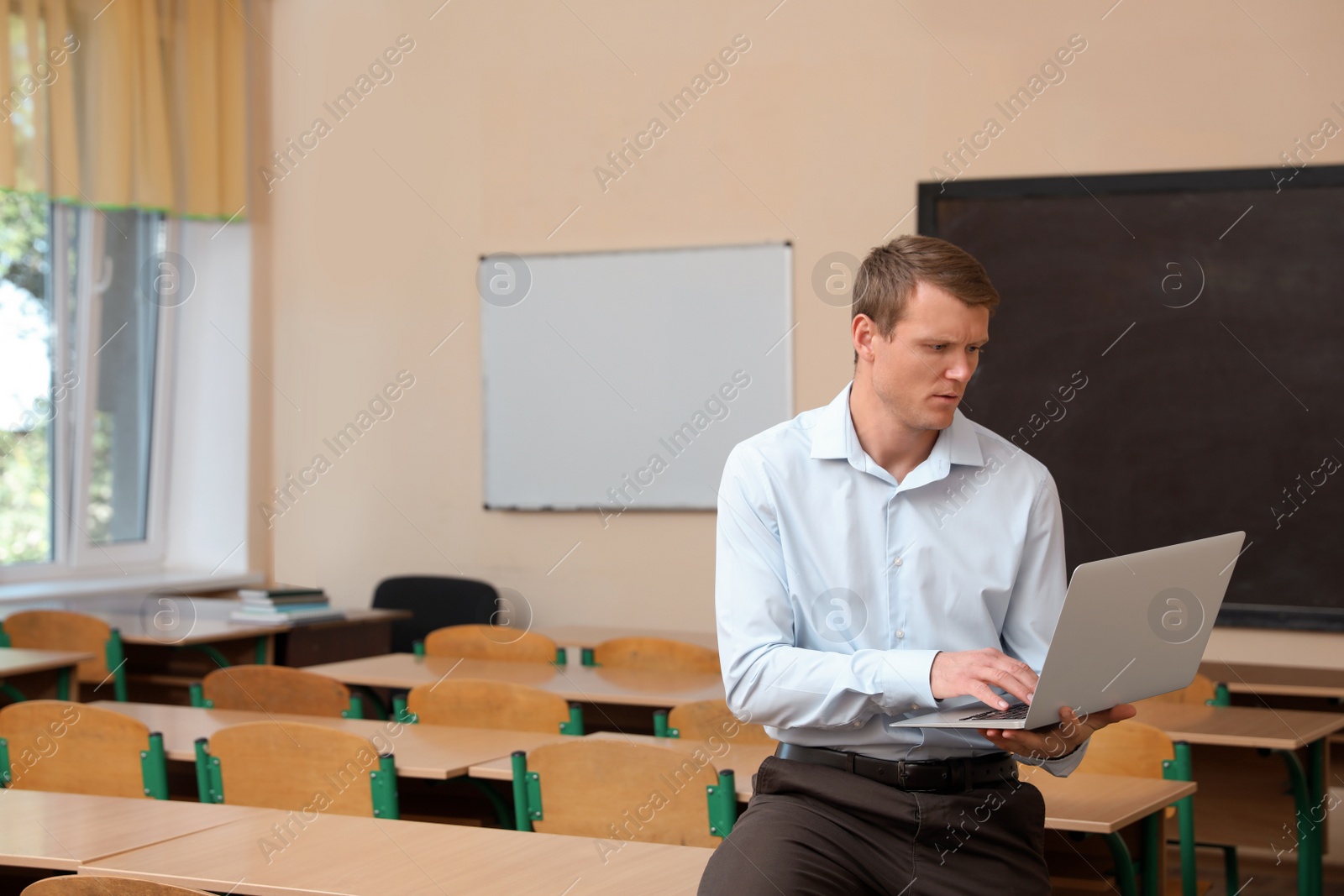 Photo of Portrait of male teacher with laptop in modern classroom