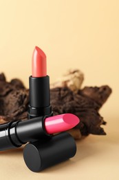 Photo of Beautiful glossy pink lipsticks on beige background