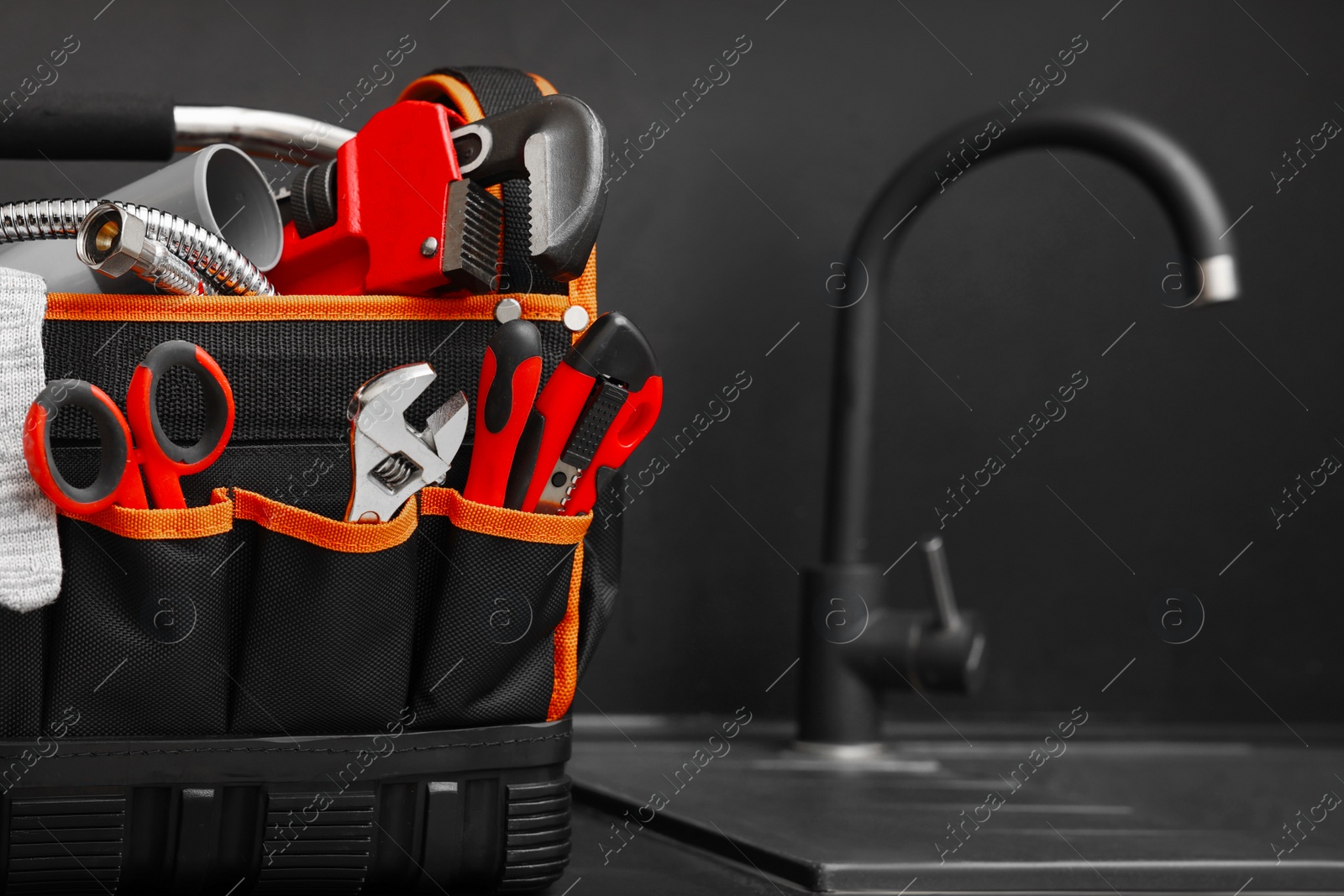 Photo of Plumber's tool bag on kitchen counter near sink, space for text