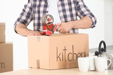 Man packing cardboard box indoors, closeup. Moving day