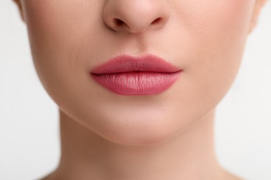 Young woman with beautiful full lips on white background, closeup