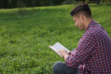 Photo of Man reading book on green grass outdoors