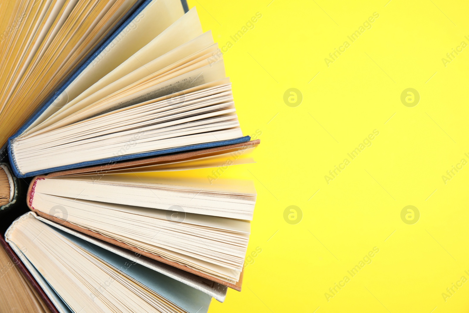 Photo of Hardcover books on yellow background, flat lay. Space for text