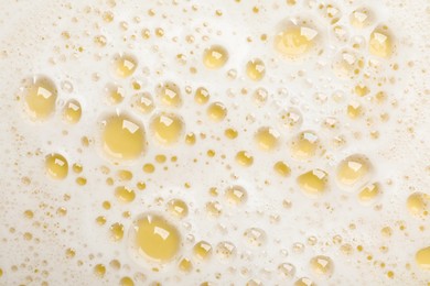 White washing foam on yellow background, top view