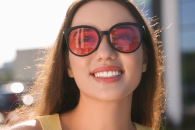 Beautiful smiling woman in sunglasses outdoors on sunny day