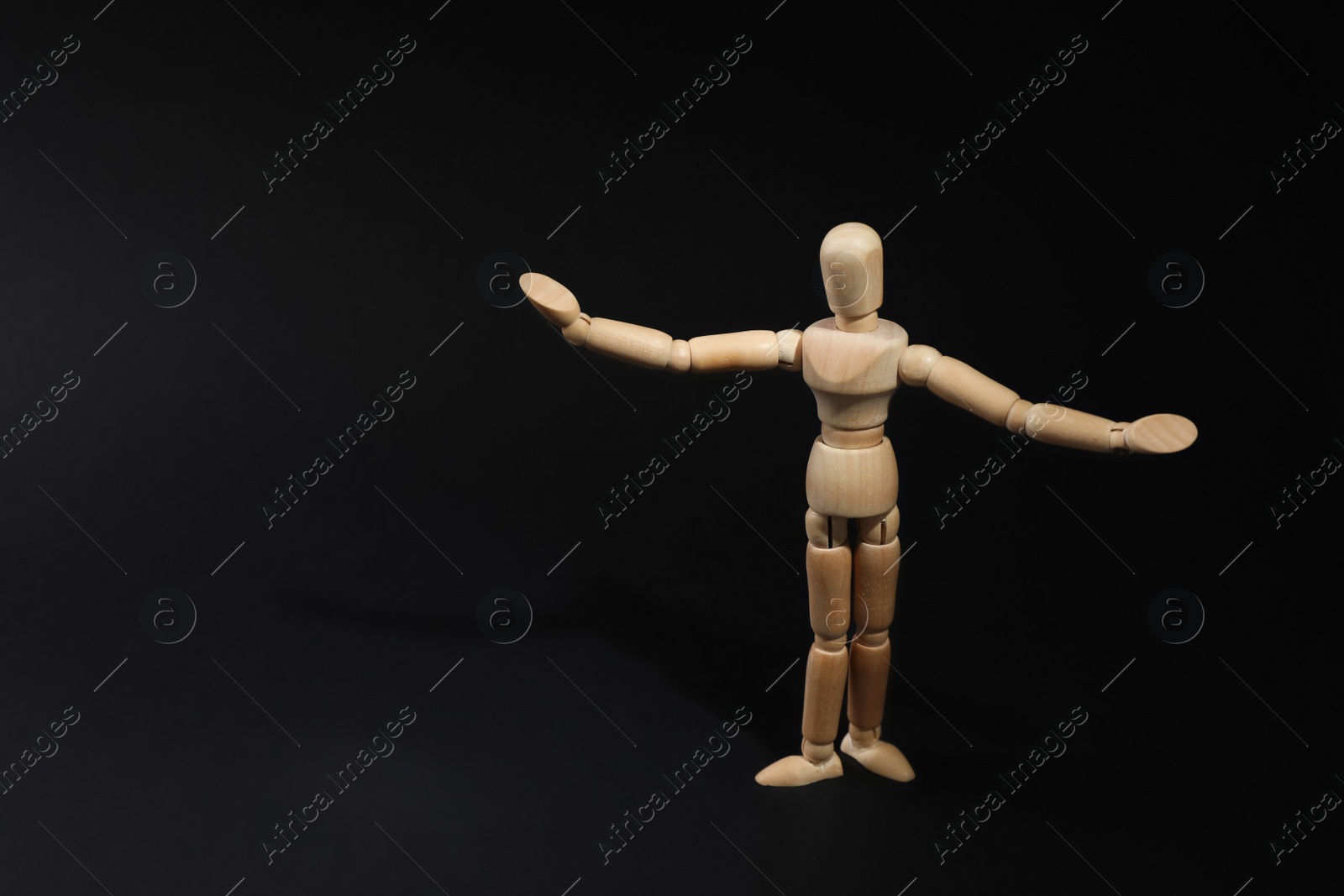 Photo of Wooden human model on black background, space for text. Mini mannequin