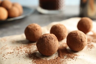 Tasty chocolate truffles on parchment paper, closeup