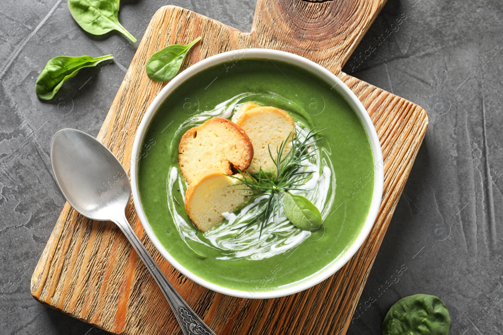 Photo of Fresh vegetable detox soup made of spinach with croutons in dish served on table, flat lay